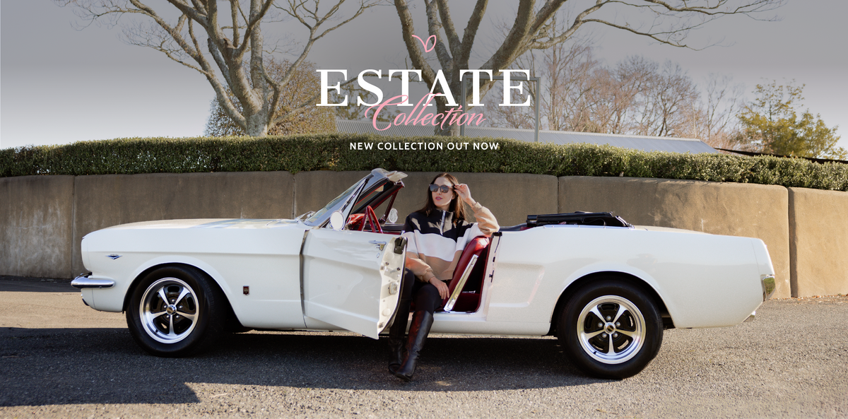 A woman posing in a white classic convertible car with the door open, set against a background of a beige wall, hedges, and bare trees. A large text overlay reads 'ESTATE Collection NEW COLLECTION OUT NOW'.