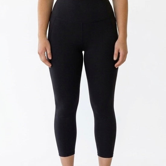 Woman wearing black 7/8 tights with no-roll-down waistband and phone pockets