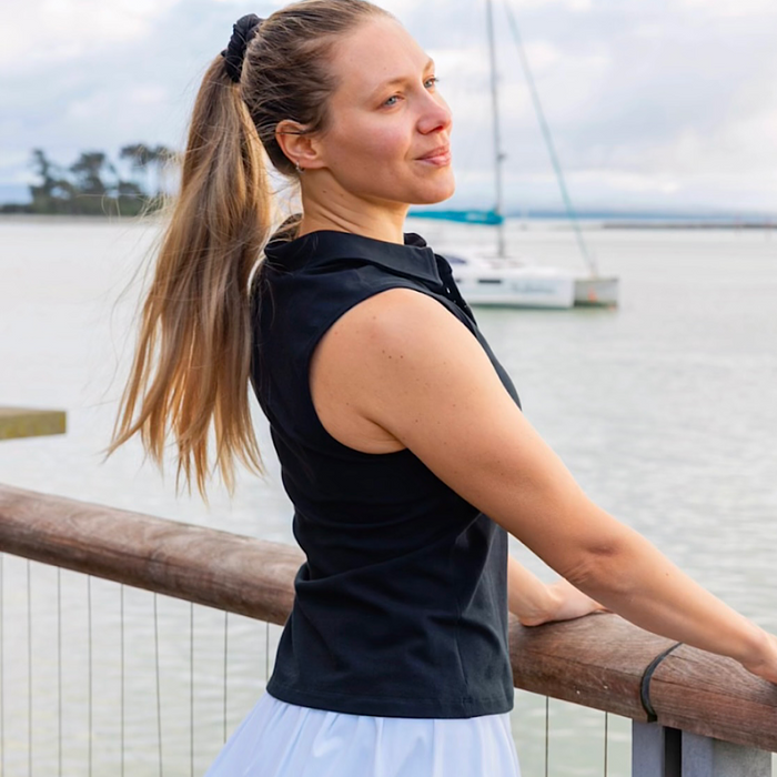 Woman wearing a black sleeveless golf polo top.