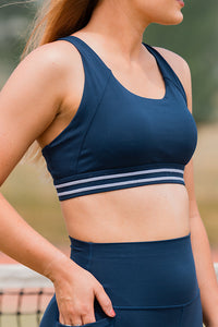 Woman wearing a navy pull over sports bra 