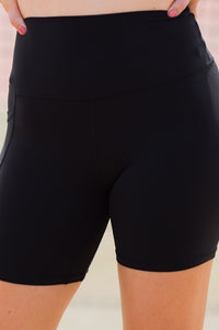 Women wearing black high-waisted shorts with phone pockets and an orange high coverage sports bra.