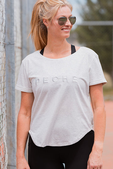 Woman wearing a grey t-shirt with 'PECHE' branding.