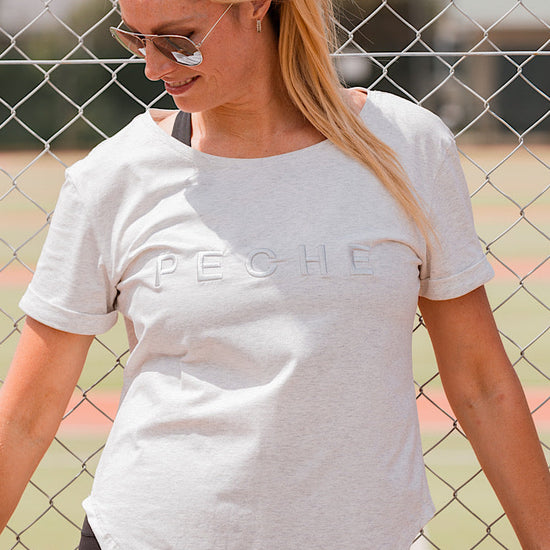 Woman wearing a grey t-shirt with scoop neck.