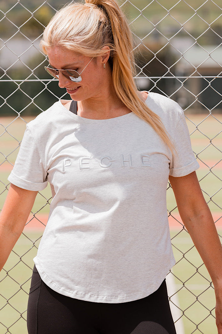 Woman wearing a grey t-shirt with scoop neck.