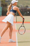 Women wearing a soft navy sports bra and white tennis skort.
