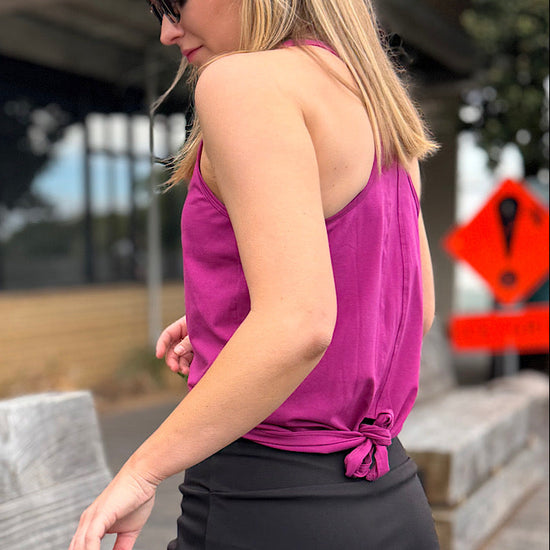 Woman wearing a magenta racer back tank top and black skort