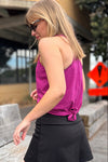 Woman wearing a magenta racer back tank top and black skort