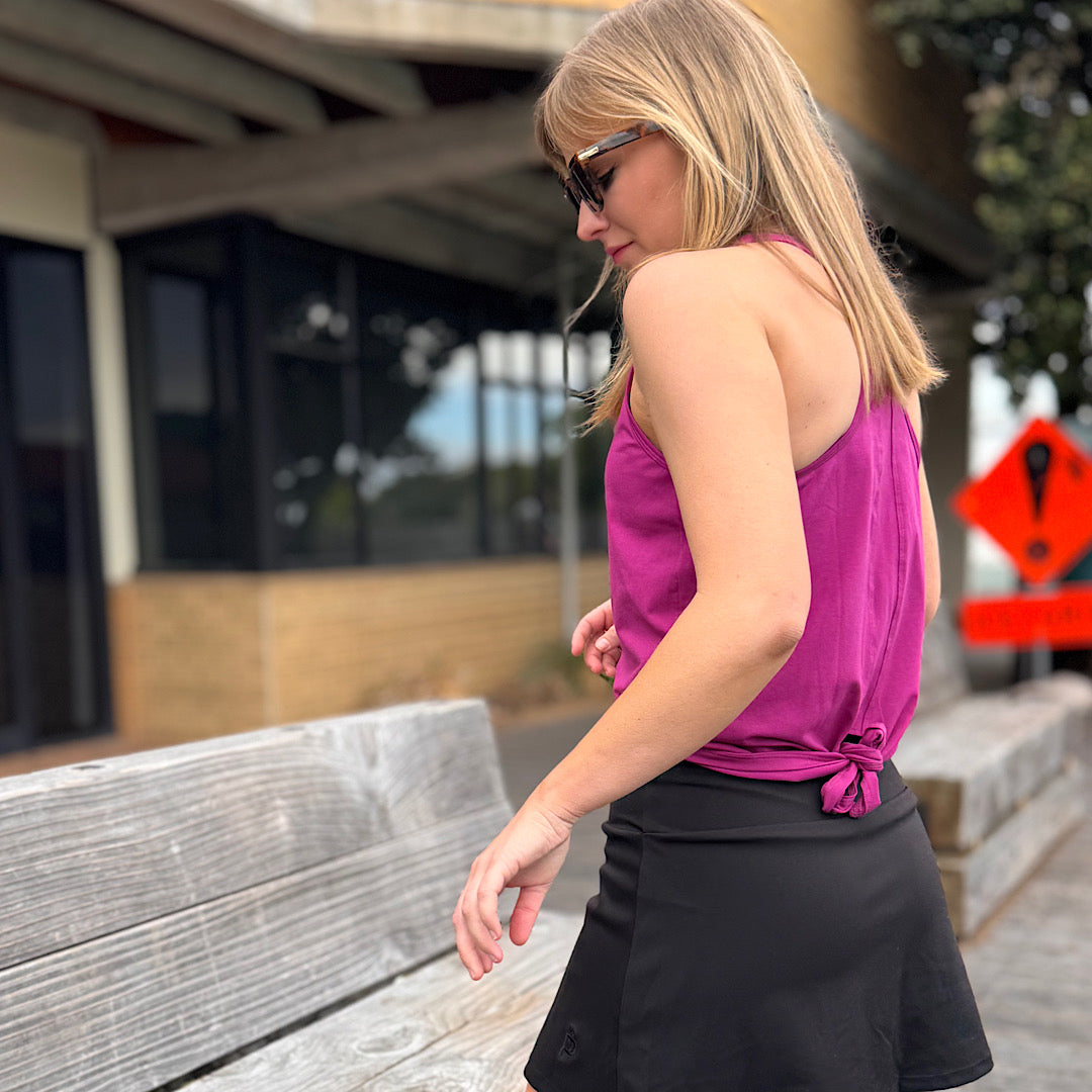 Woman wearing a magenta racer back tank top and black skort