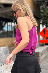 Woman wearing a magenta racer back tank top and black skort