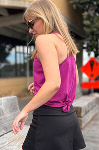 Woman wearing a magenta racer back tank top and black skort