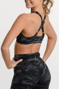 A woman shown from the back wearing a matching black and gray camouflage activewear set, featuring a sports bra and high-waisted biker shorts, against a plain white studio background.