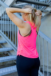 Woman wearing a bright pink tank top and black phone pocket leggings