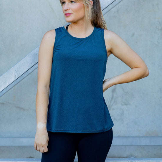 Woman wearing a relaxed teal sleeveless top and black high waisted tight