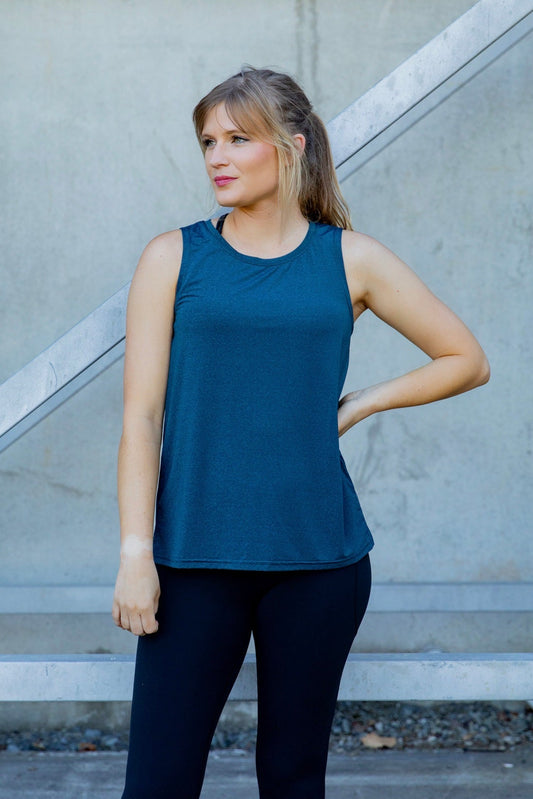 Woman wearing a relaxed teal sleeveless top and black high waisted tight