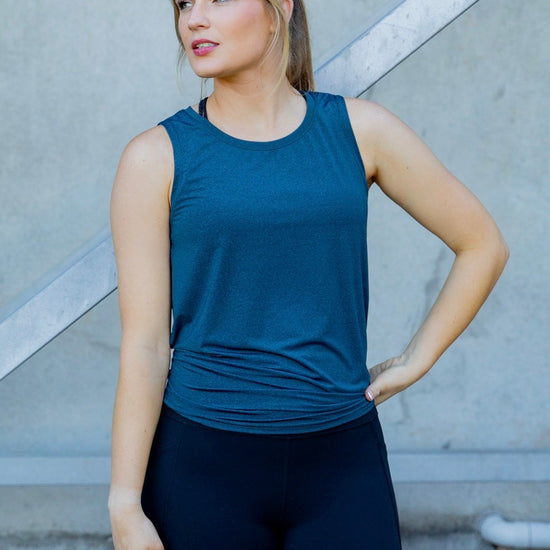 Woman wearing a blue sleeveless top and black high waisted leggings 