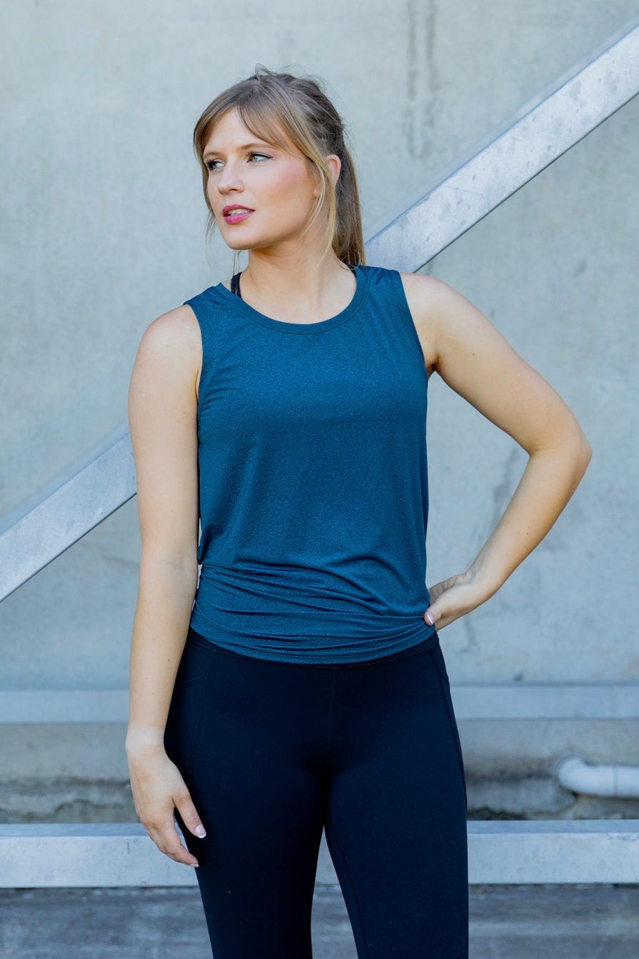 Woman wearing a blue sleeveless top and black high waisted leggings 