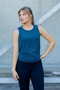 Woman wearing a blue sleeveless top and black high waisted leggings 