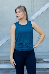 Woman wearing a blue sleeveless top and black high waisted leggings 