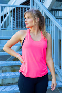 Woman wearing a bright pink tank top and black phone pocket leggings
