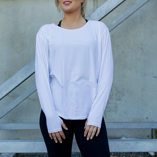 Woman wearing a white long-sleeve uv top and black non roll down leggings.