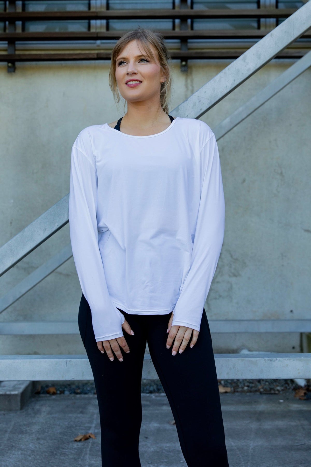 Woman wearing a white long-sleeve uv top and black non roll down leggings.
