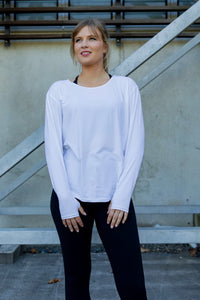 Woman wearing a white long-sleeve uv top and black non roll down leggings.