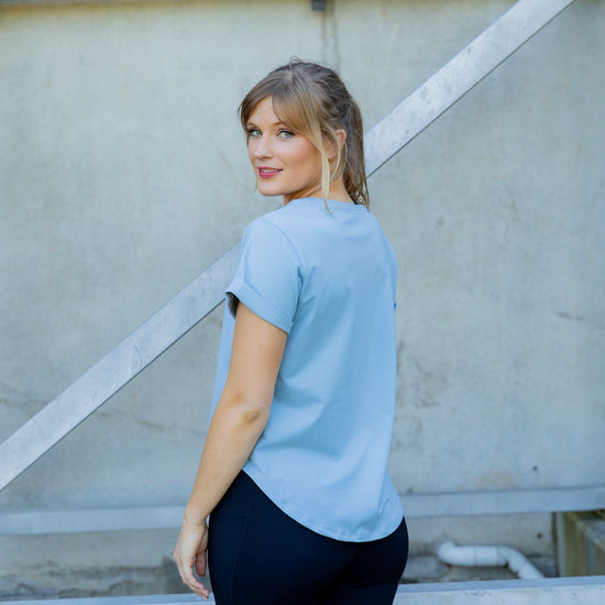 Woman wearing a scoop neck light blue t-shirt and black high waisted leggings