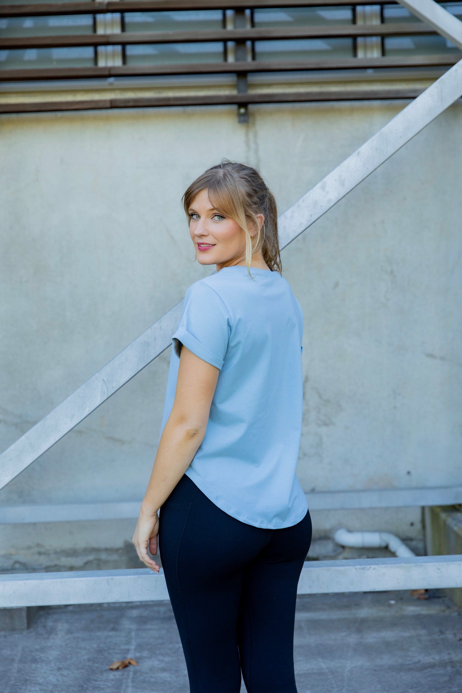 Woman wearing a scoop neck light blue t-shirt and black high waisted leggings