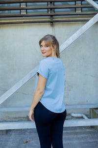 Woman wearing a scoop neck light blue t-shirt and black high waisted leggings