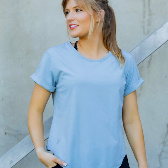 Woman wearing a scoop neck light blue t-shirt and black high waisted leggings