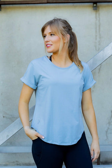 Woman wearing a scoop neck light blue t-shirt and black high waisted leggings