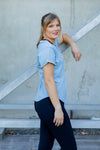 Woman wearing a scoop neck light blue t-shirt with rolled sleeves and black high waisted leggings