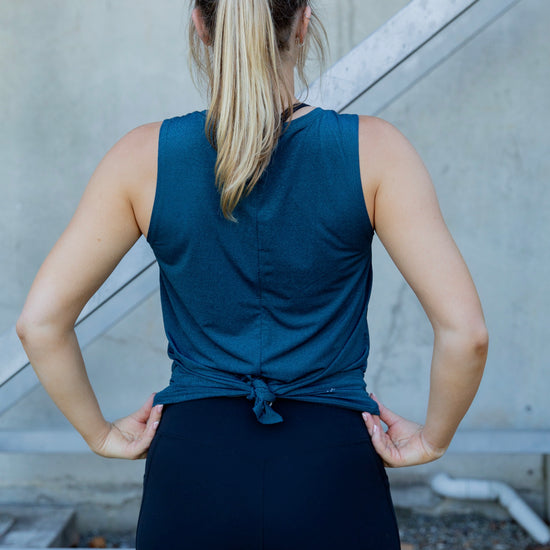 Woman wearing a relaxed teal sleeveless top and black high waist tight
