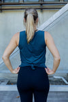 Woman wearing a relaxed teal sleeveless top and black high waist tight