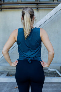 Woman wearing a relaxed teal sleeveless top and black high waist tight