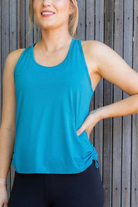 Woman in an aqua singlet and black phone pocket leggings 