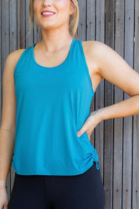 Woman in an aqua singlet and black phone pocket leggings 