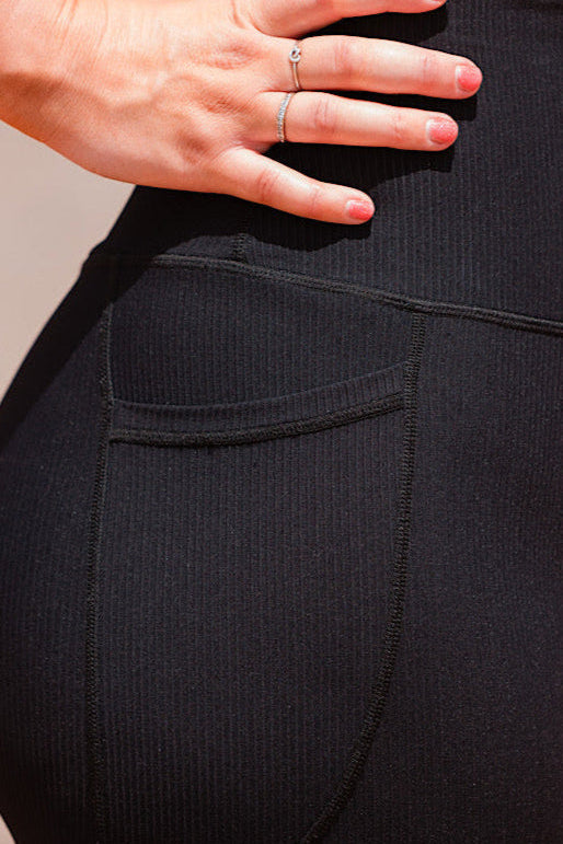 Women wearing ribbed black high waist leggings with phone pockets.