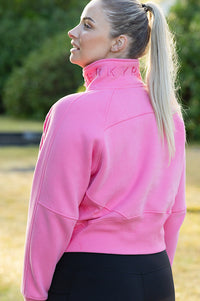 Woman wearing a pink cropped half zip hoodie.