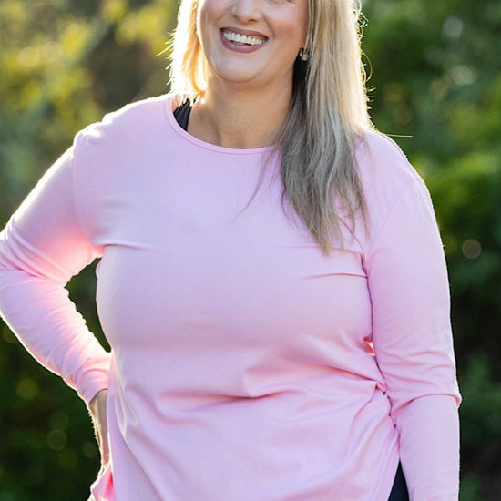 Curvy woman wearing a pink long-sleeve top 