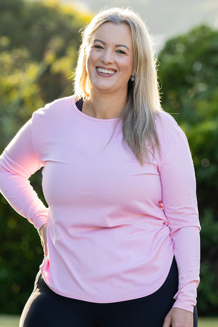 Curvy woman wearing a pink long-sleeve top 