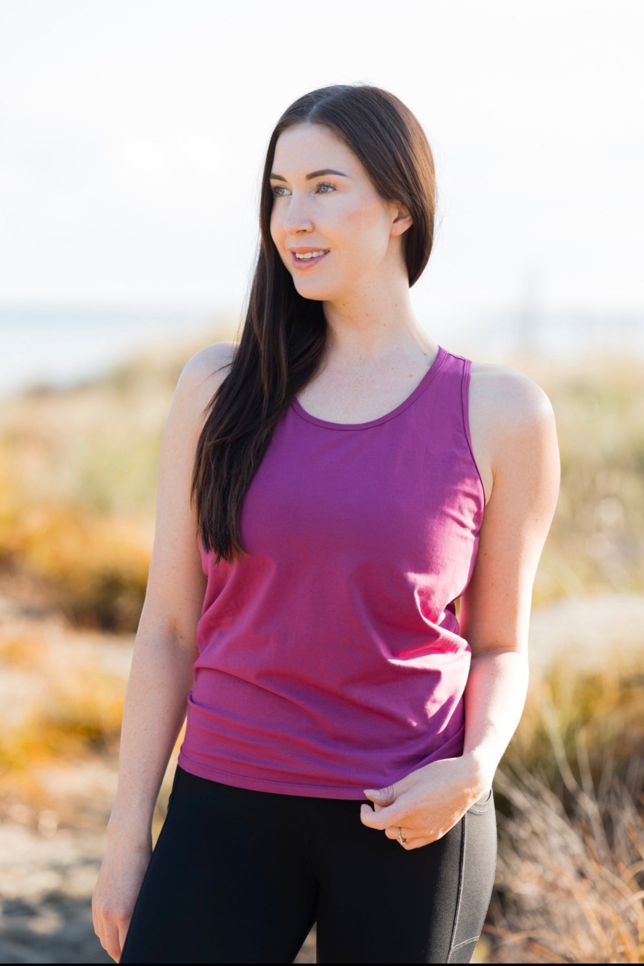 Woman wearing a magenta racer back tank top.