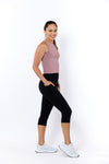 Woman wearing a sleeveless top and black 3/4 high-waisted leggings with phone pockets