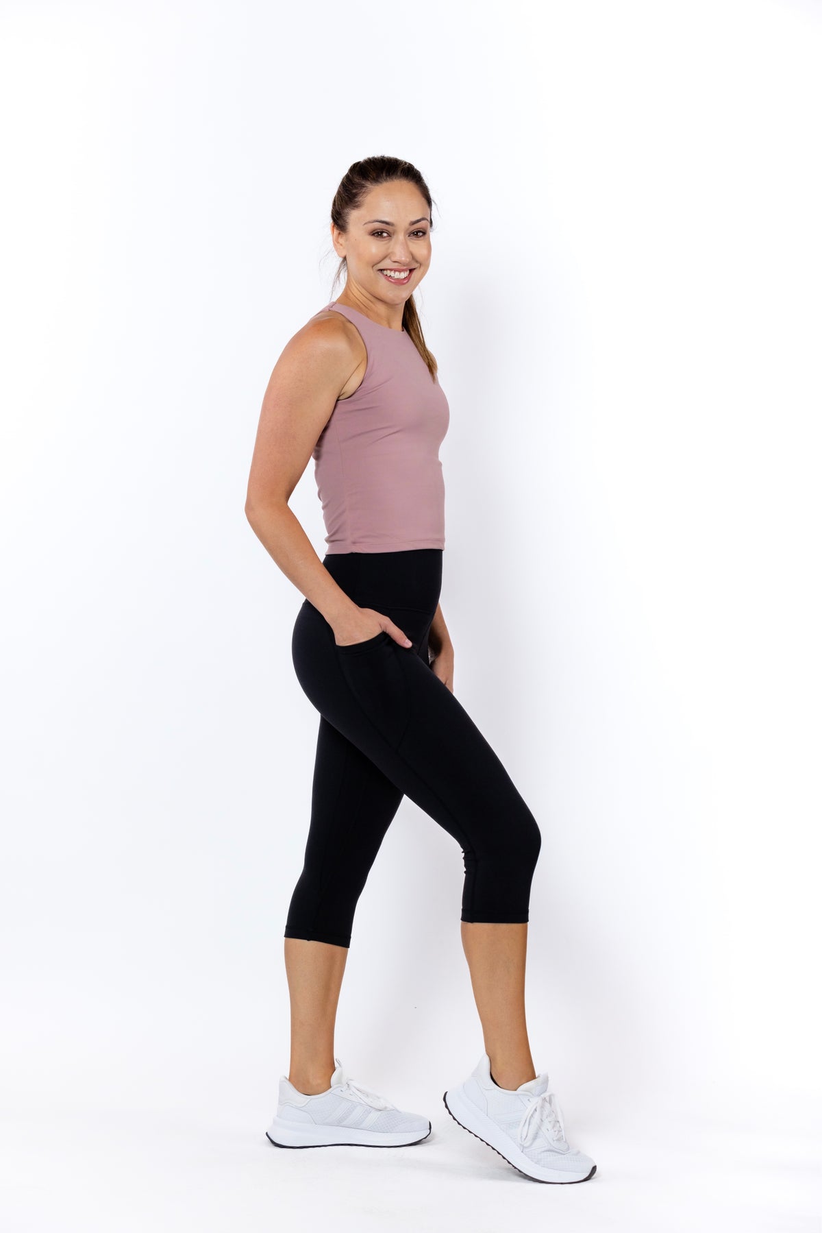 Woman wearing a sleeveless top and black 3/4 high-waisted leggings with phone pockets