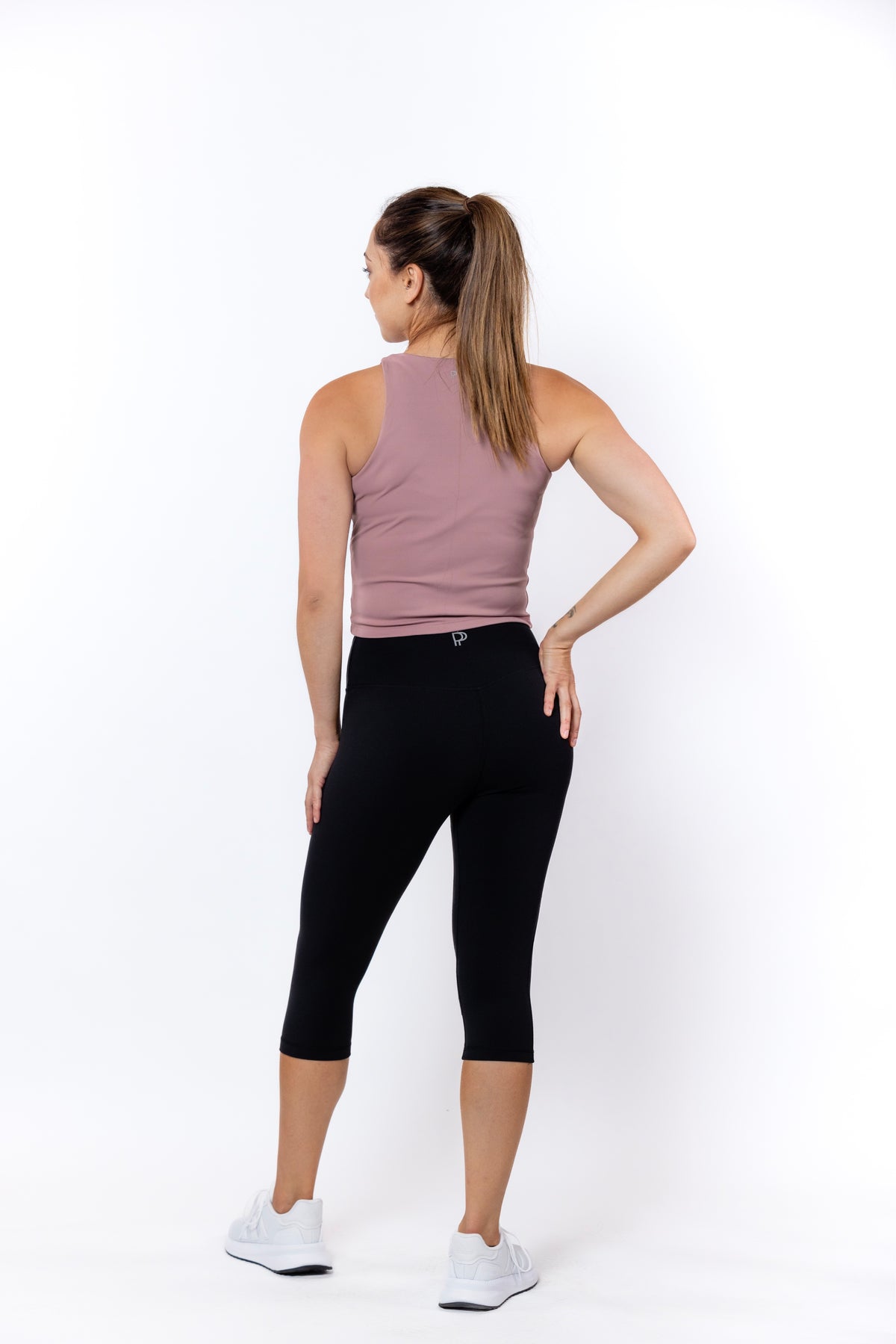 Woman wearing a pink tank top and black capri leggings