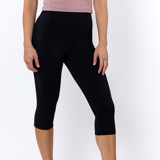 Person wearing black capri leggings and a pink top