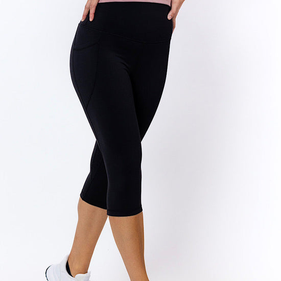 Woman wearing black 3/4 tights with no-roll-down waistband and white sneakers