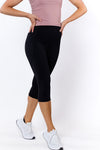 Woman wearing black 3/4 tights with no-roll-down waistband and white sneakers