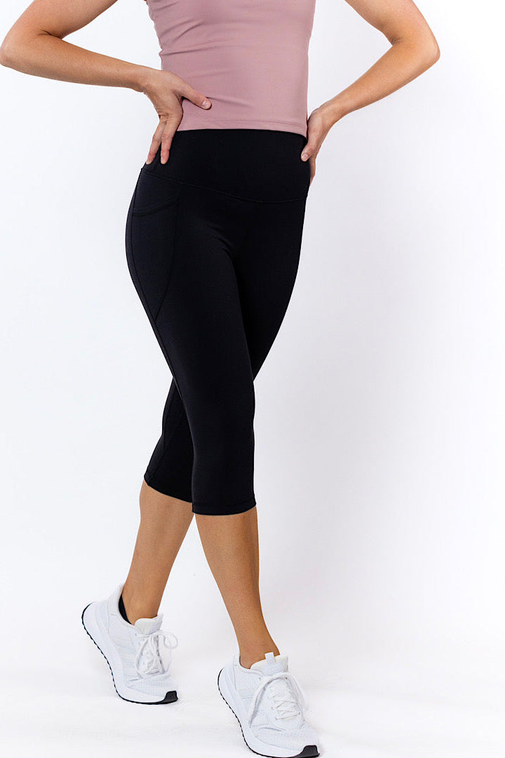 Woman wearing black 3/4 tights with no-roll-down waistband and white sneakers
