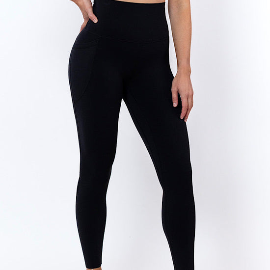Women wearing high waisted black phone pocket leggings and a navy bra